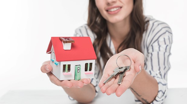 21552023-beautiful-young-woman-holding-house-model-with-keys-and