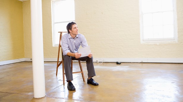 2130286-man-sitting-on-ladder-in-empty-space-holding-paper
