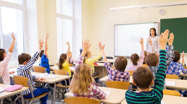 12838484-group-of-school-kids-raising-hands-in-classroom
